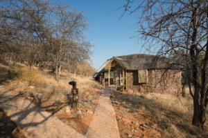 Rock-and-thatch Ongava Lodge chalet on the hillside