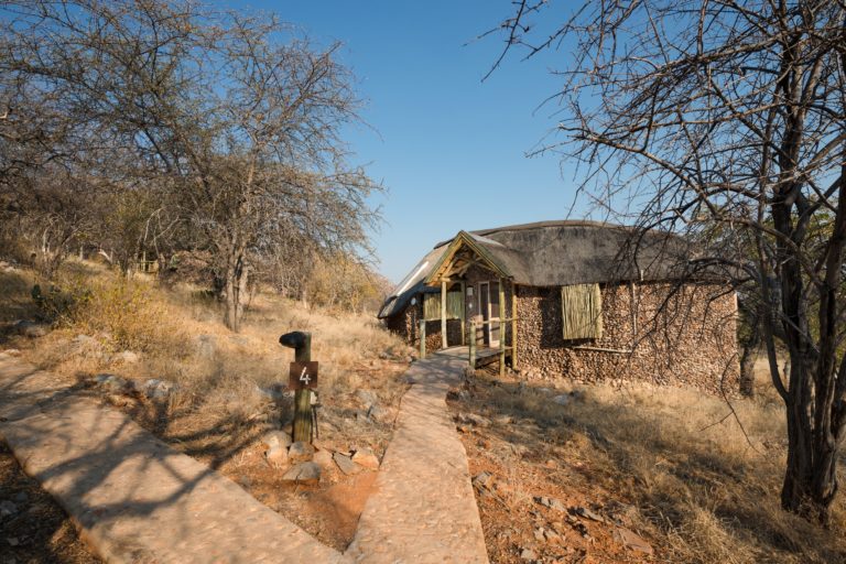 Rock-and-thatch Ongava Lodge chalet on the hillside