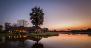 Onguma Bush Camp waterhole and lodge at sunset