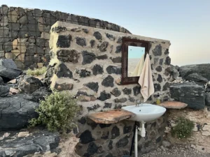 Outdoor shower beside a stone chalet wall at Fish River Lodge