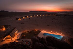 Desert Quiver accommodation – camp lights across the desert at sunset