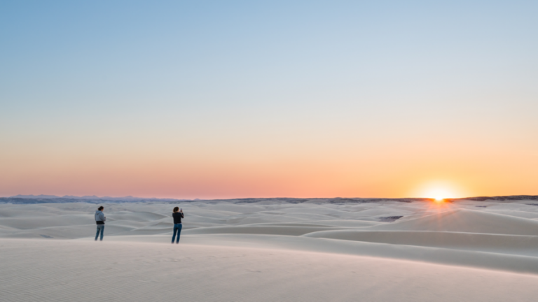 luxury lodge on the Skeleton Coast – guests watching sunset from coastal dunes