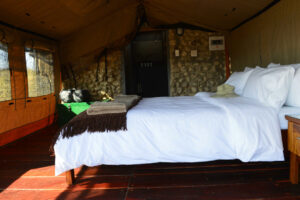 Khaudum Sikereti Camp – double bed and stone feature inside a tented unit