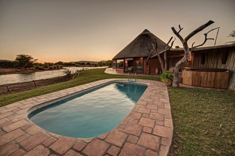 Namibia safari lodge – swimming pool beside thatched guest rooms