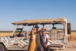 Etosha King Nehale safari guests beside an open game-drive vehicle