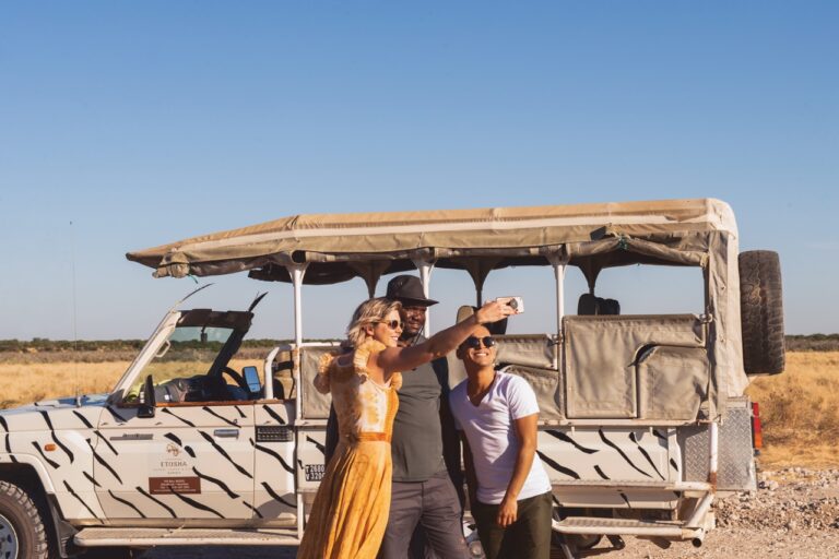 Etosha King Nehale safari guests beside an open game-drive vehicle