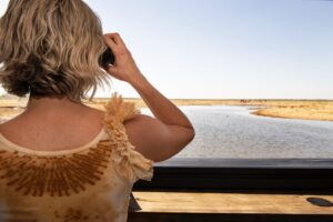 Guest using binoculars at the King Nehale accommodation waterhole hide
