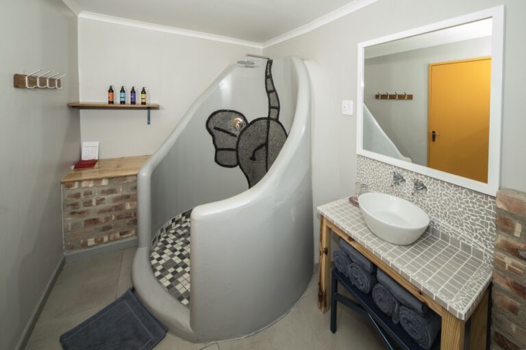 Walk-in elephant-motif shower in a camp chalet