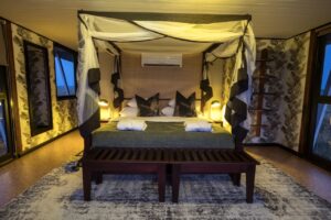 Mosquito-netted bedroom at Namushasha River Villa after dark