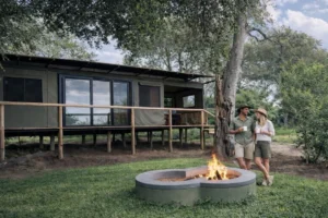 Guests beside a tent and lit fire pit at Buffalo Tented Camp