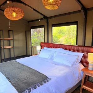Furnished tent bedroom with double bed at Buffalo Tented Camp