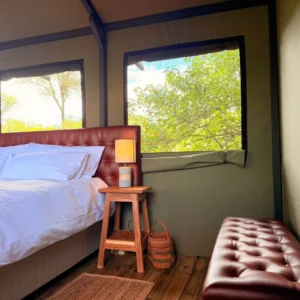 Bed, window and cushioned bench inside a Buffalo Tented Camp tent