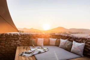 Cushioned seating beside a stone wall at Desert Rhino Camp