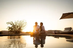 Guests beside the Desert Rhino Camp pool at sunset