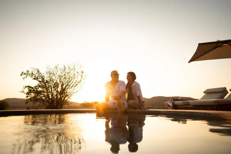Guests beside the Desert Rhino Camp pool at sunset