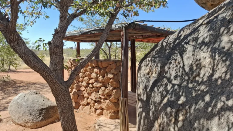 Shaded campsite kitchen area among trees and rocks at Hoada