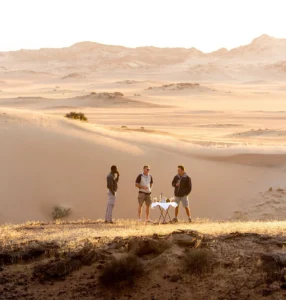 Guests enjoying sundowners in dunes near Hoanib Skeleton Coast Camp