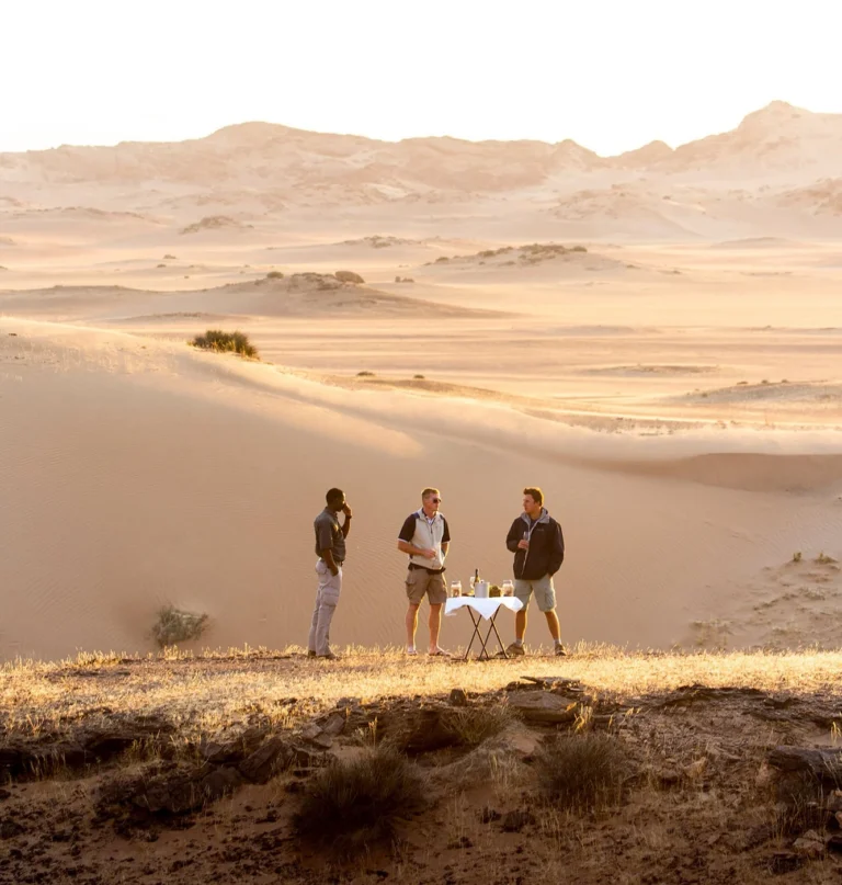 Guests enjoying sundowners in dunes near Hoanib Skeleton Coast Camp