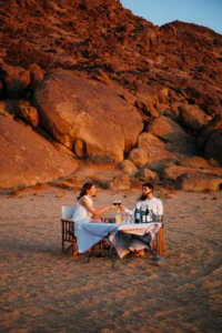 Guests enjoying sundowners beside a rocky outcrop near Kulala Desert Lodge
