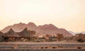 Little Kulala lodge buildings beneath the mountains at sunrise