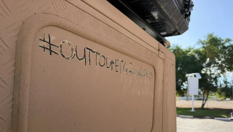 Outtogetgrowcerys written in dust on the side of a travelling vehicle