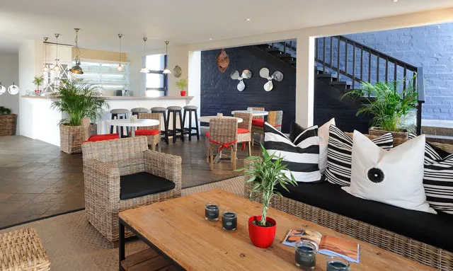 Tables, chairs and plants in the Oyster Box Guesthouse lounge